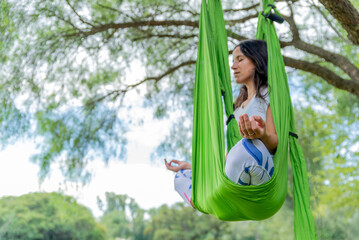 Woman Meditating on an Aerial Yoga Hammock in the Nature.Copy pace