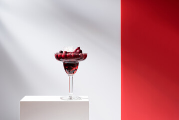 Cóctel margarita de arándanos rojos sobre un soporte blanco y fondo gris	