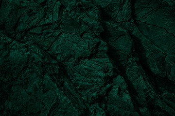 Dark green rock texture. Cracked layered mountain surface. Close-up. Grungy stone background with...