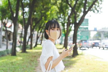 Young adult business asian working woman wear face mask at nature public park.