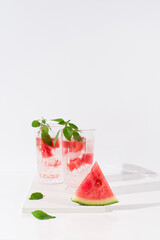 Dos vasos de zumo de sandía con trozos de sandia y hielo sobre fondo claro	