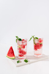 Dos vasos de zumo de sandía con trozos de sandia y hielo sobre fondo claro	