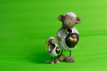Spring theme. Pair of ceramic sheep, same, one is bigger, like mother and baby, isolated on green...