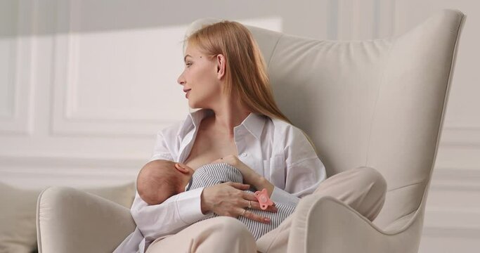 Mom breastfeeds baby. Mom talks to the eldest son and at the same time feeds the baby.