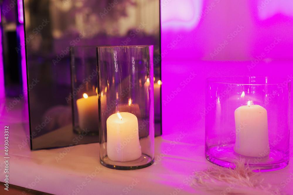 Wall mural burning candles in glass vases are on the table on the wedding day in restaurant. violet light.