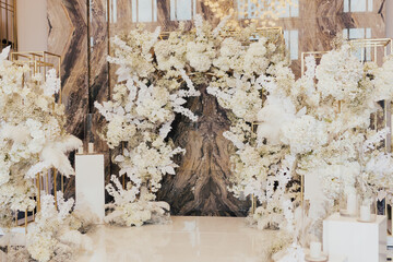 Wedding arch at the luxury restaurant. White flower arch. Trend in the wedding banquet room is marble background.