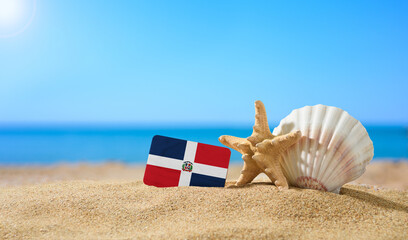 Tropical beach with seashells and Dominican flag. The concept of a paradise vacation on the beaches...