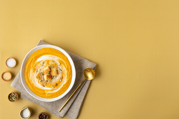 Banner pumpkin puree soup with cream, toast and seeds on a colored background with copy space. Top...