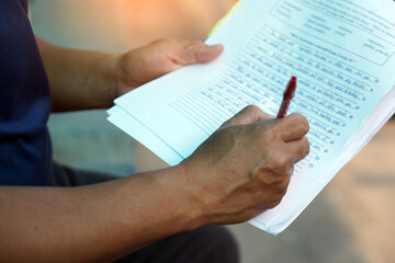 Closeup teacher's hand holds pen to check and correct paper test. Concept : Education evaluation....
