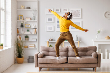 African American meloman dancing on couch