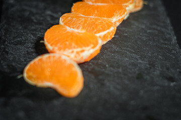Fototapeta na wymiar Tangerine segments on black stone tray.