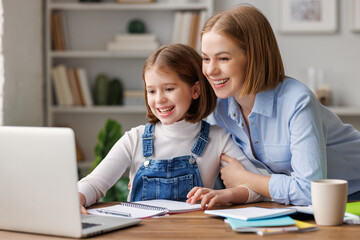 Fototapeta premium Cheerful mother doing homework with daughter at home