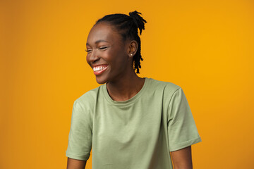 Portrait of beautiful positive african american woman in yellow studio