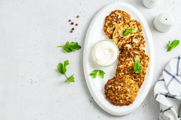 Broccoli chicken fritters on white dish with sour cream sauce. Top view, space for text.