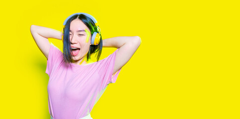 Young asiatic woman listening music laughing isolated background - copyspace cropped banner