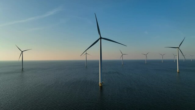Wind turbines producing sustainable renewable energy in an offshore wind parkt. Drone point of view.