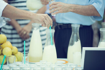 Mesa de limonada fresca en un catering con personas sirviéndose refrescos de limón en vasos