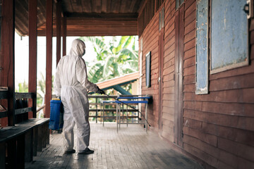 A man wearing protective suits masks and disinfectant tank spray.Big cleaning and disinfection of school amid coronavirus outbreak, infection prevention, and an epidemic of covid-19 control.