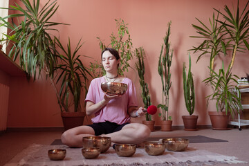 a young woman sits on the floor and works with Tibetan bowls