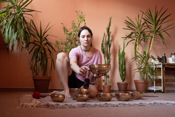 a young woman sits on the floor and works with Tibetan bowls