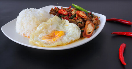Rice with pork stir fried with basil and fried egg on black background, Thai food, Street food.