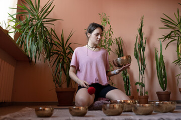 a young woman sits on the floor and works with Tibetan bowls