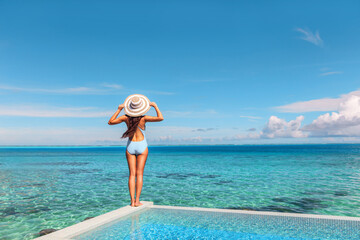 Luxury vacation hotel in Tahiti woman relaxing at infinity pool looking over ocean in French...