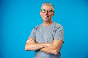 Portrait of senior man with arms crossed over blue background
