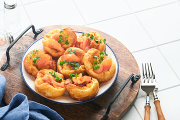 Yorkshire pudding. Traditional English Yorkshire pudding with salmon and radish microgreens side dish on white plate and light grey background table. Top view.