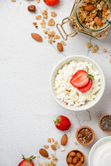 Cottage cheese strawberries, yogurt with granola, nuts on a white concrete background with copy space. Healthy breakfast concept. Flat lay.