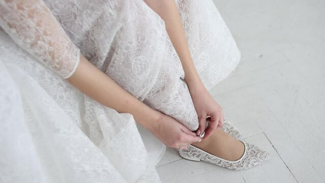 bride in a wedding dress puts on flat shoes