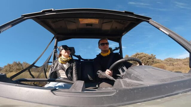 Young couple driving a buggy UTV ATV Can-am polaris on desert off-road in Ronda, Spain, on a sunny day . Couple having fun riding a ATV off-road