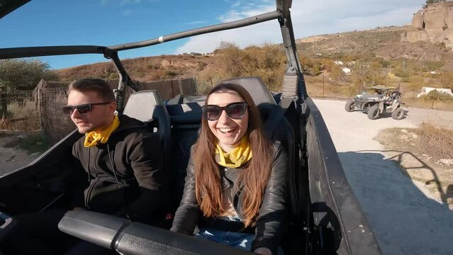 Young couple driving a buggy UTV ATV Can-am polaris on desert off-road in Ronda, Spain, on a sunny day . Couple having fun riding a ATV off-road