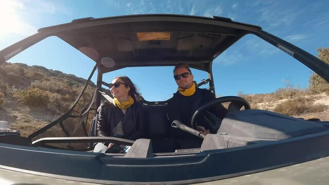 Young couple driving a buggy UTV ATV Can-am polaris on desert off-road in Ronda, Spain, on a sunny day . Couple having fun riding a ATV off-road