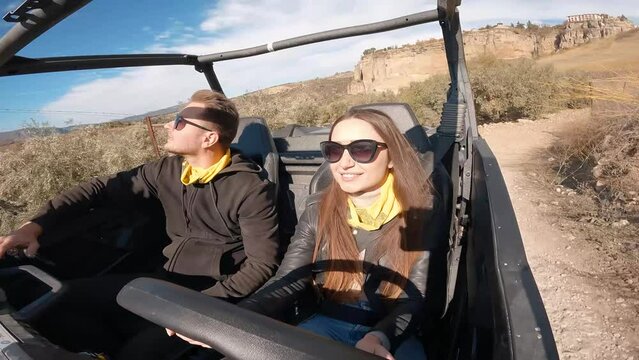 Young couple driving a buggy UTV ATV Can-am polaris on desert off-road in Ronda, Spain, on a sunny day . Couple having fun riding a ATV off-road