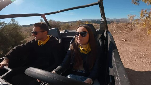 Young couple driving a buggy UTV ATV Can-am polaris on desert off-road in Ronda, Spain, on a sunny day . Couple having fun riding a ATV off-road