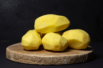 Peeled potatoes on a black background. Delicious and healthy vegetable. food preparation ingredient