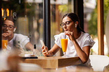 A millennial in a bar refreshing and hanging on phone..