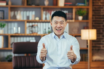Successful asian man in shirt working late in classic office, portrait of happy businessman looking...
