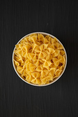 Raw Organic Farfalle Pasta in a Bowl on a black background, top view. Flat lay, overhead, from above.