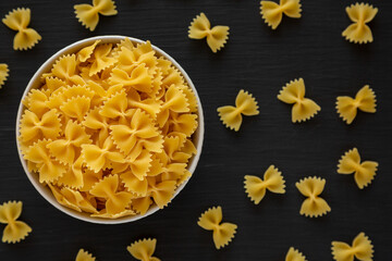 Raw Organic Farfalle Pasta in a Bowl on a black background, top view. Flat lay, overhead, from above.