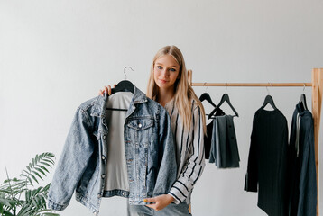 Young woman in the closet in the room showing her black Friday purchase, denim jacket