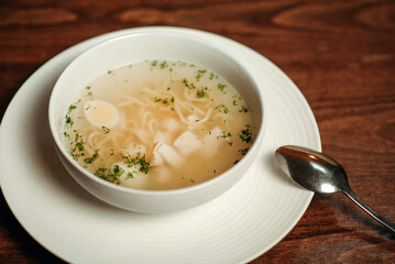 Close-up of chicken broth in a white plate with slices of bread