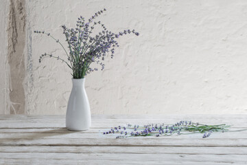 lavender in white vase on wooden table
