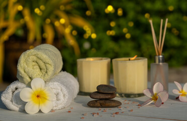 Plumeria towel with pink salt scrub, spa massage oil, aromatherapy soap and scented candle, prepare to make a spa salon.