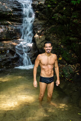 Fototapeta na wymiar Beautiful view to man enjoying waterfall on green rainforest area