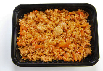 Pilaf with chicken in a plastic container. Lunch in a disposable dish.