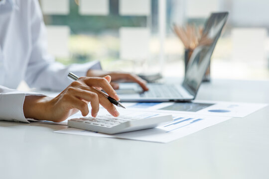 Close up of businesswoman Accounting using calculating income-expenditure and analyzing real estate investment data report Financial and tax systems concept.