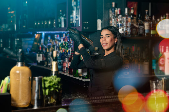 Latin brunette waitress prepares a cocktail at the bar. profession
