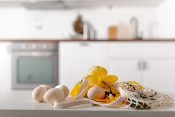 Obraz na płótnie Canvas Mesh shopper with eggs and flowers on white table.